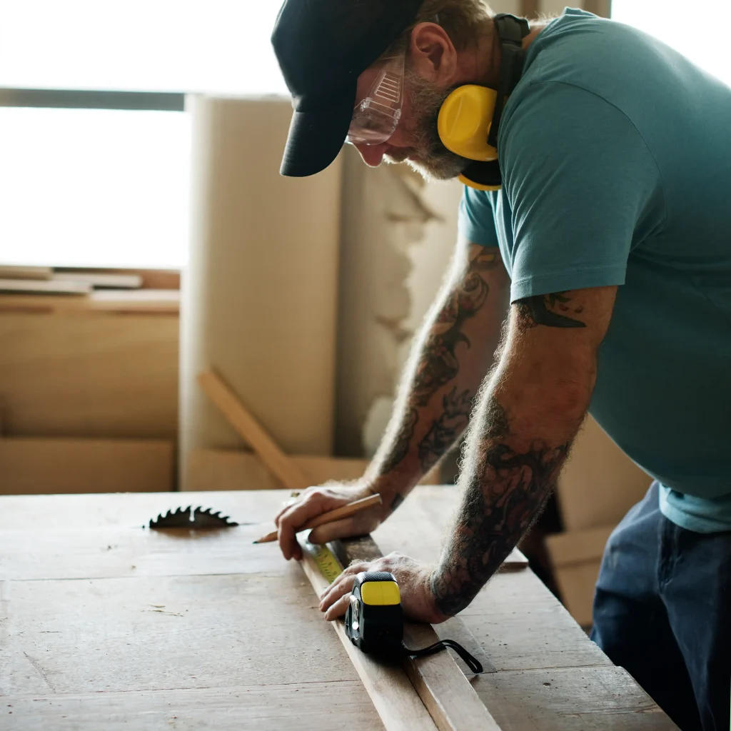 Carpenter measuring wood with tape and pencil during construction