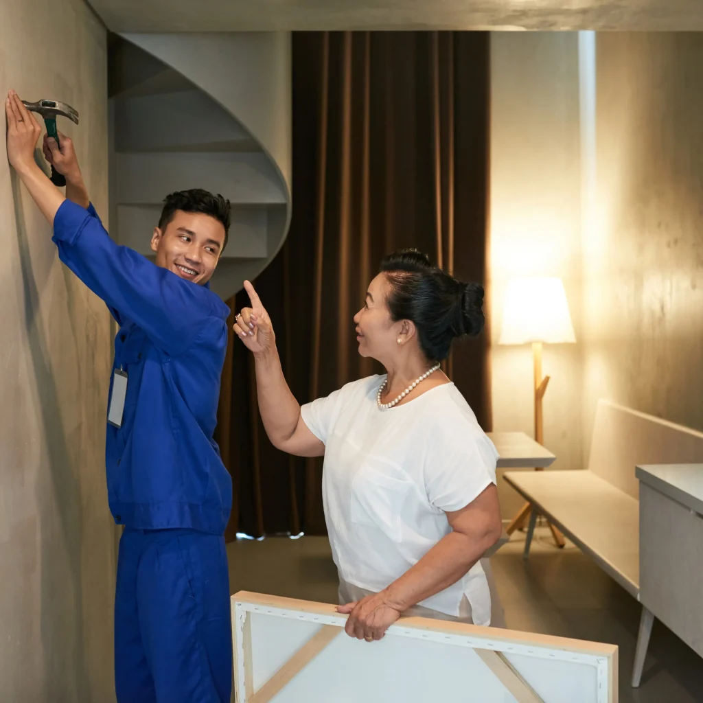 Handyman hammering a nail while homeowner gives instructions during home improvement